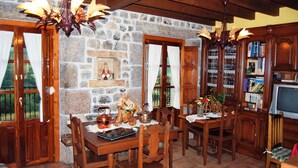Un coin repas rustique avec des murs en pierre, des meubles en bois et un lustre.