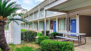 A motel with a covered walkway, multiple rooms, and a picnic table. - Motel 6 Bay Minette, AL (Bay Minette)