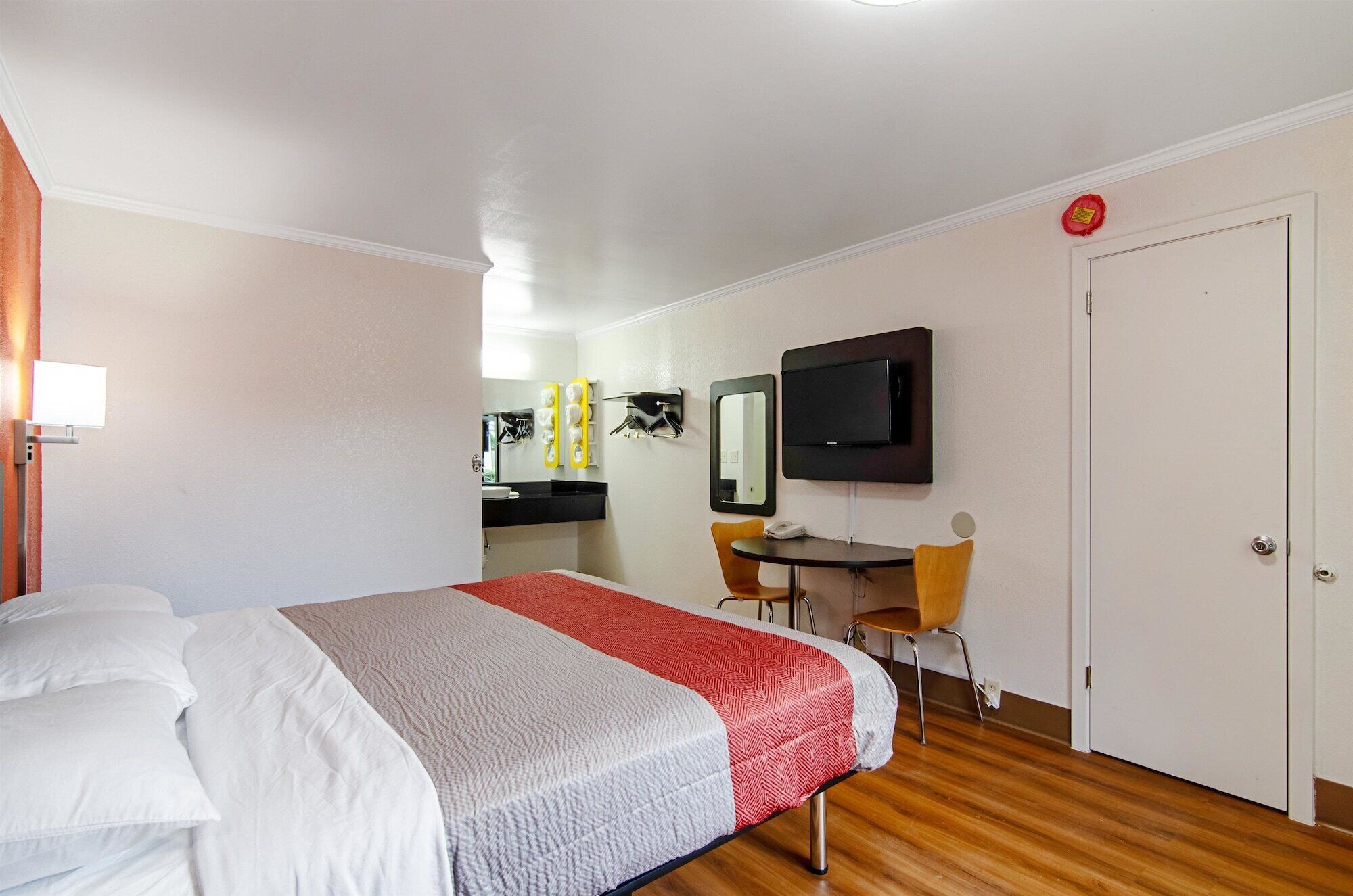 Een hotelkamer met een bed, een bureau, een stoel, een televisie en een deur.