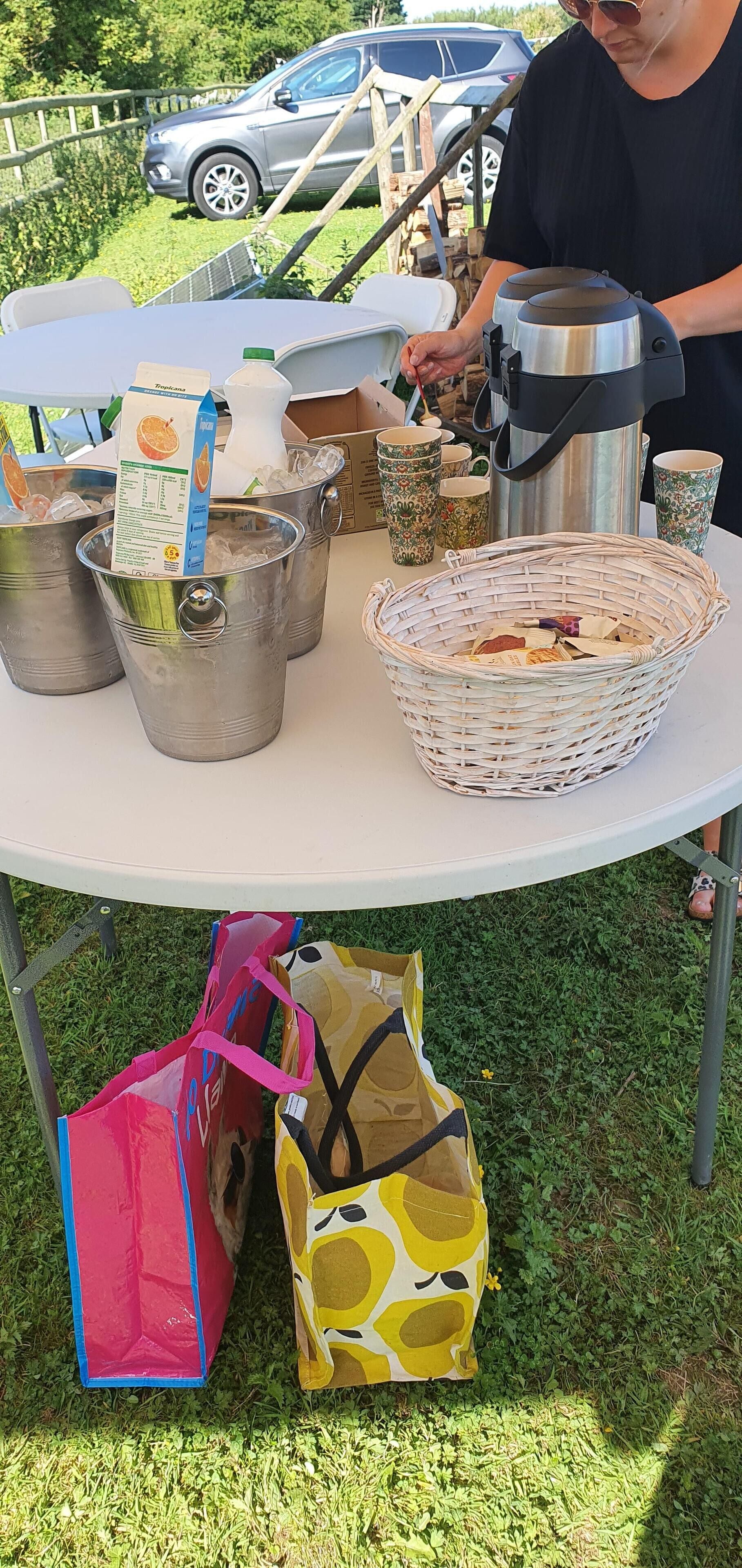 Un tavolo con secchielli, un cesto e una macchina da caffè portatile.