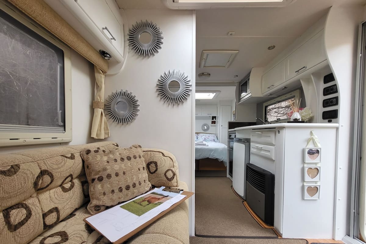 A compact RV interior with a kitchenette, a bed, and a sofa.