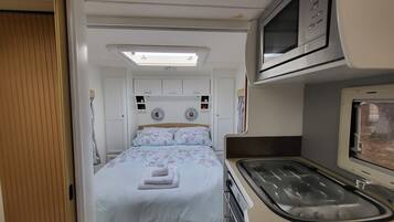 Ein kompaktes Wohnmobil-Interieur mit Bett, Küchenzeile und kleinem Badezimmer.