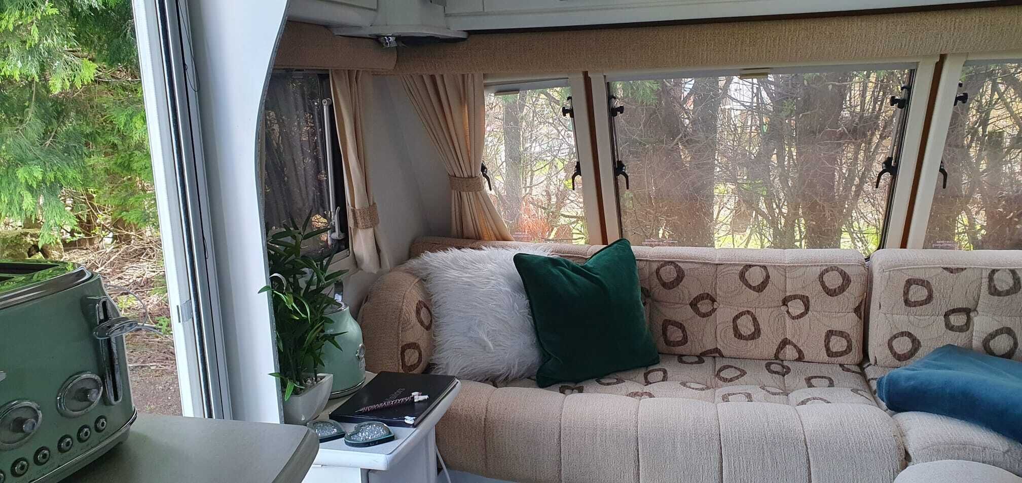 A cozy living room with a sofa, a small table, and a potted plant.