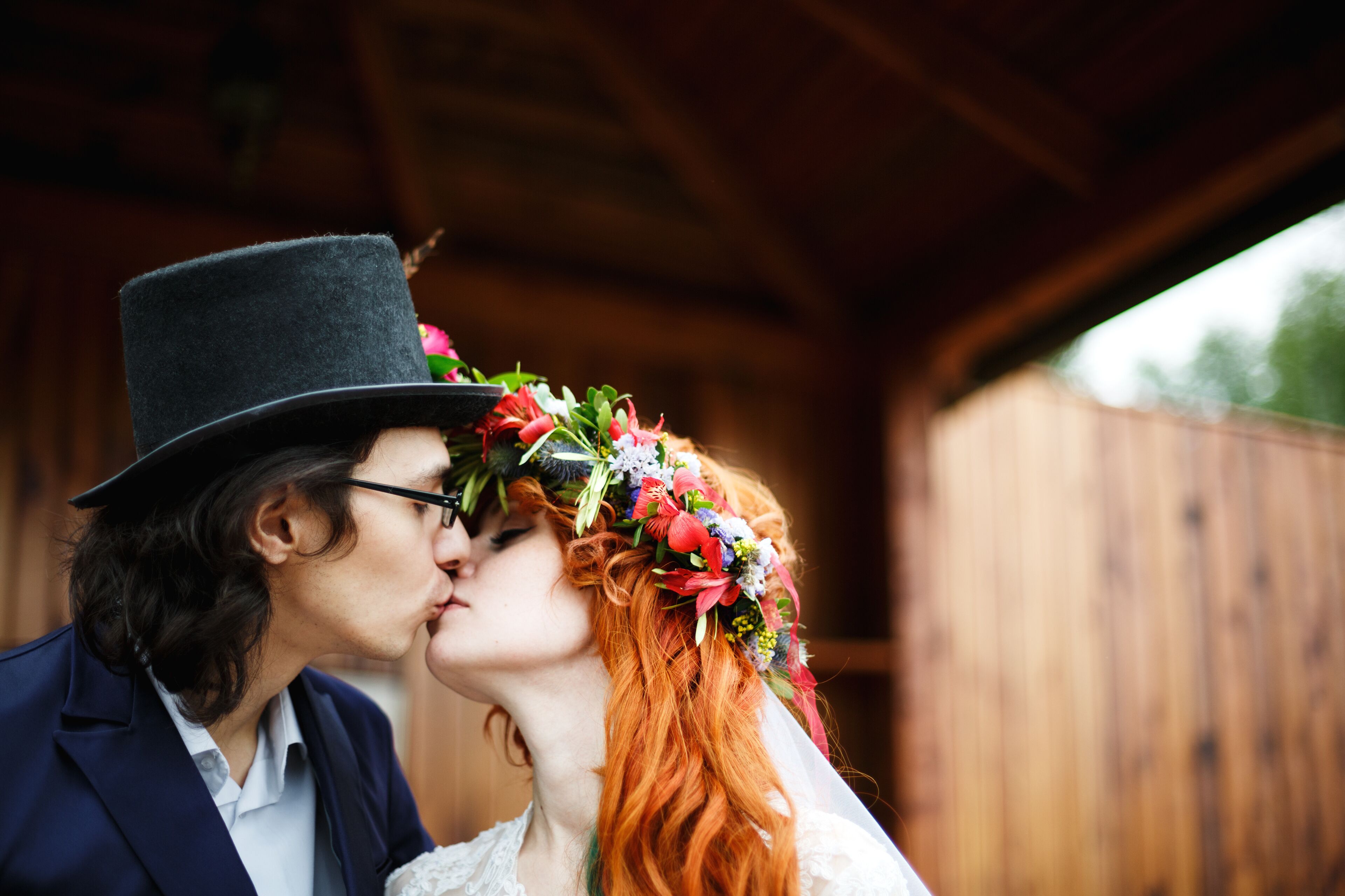 A couple embracing under a wooden structure.