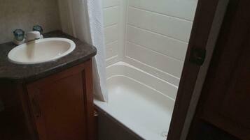 A bathroom with a white sink, wooden cabinet, and a white bathtub.