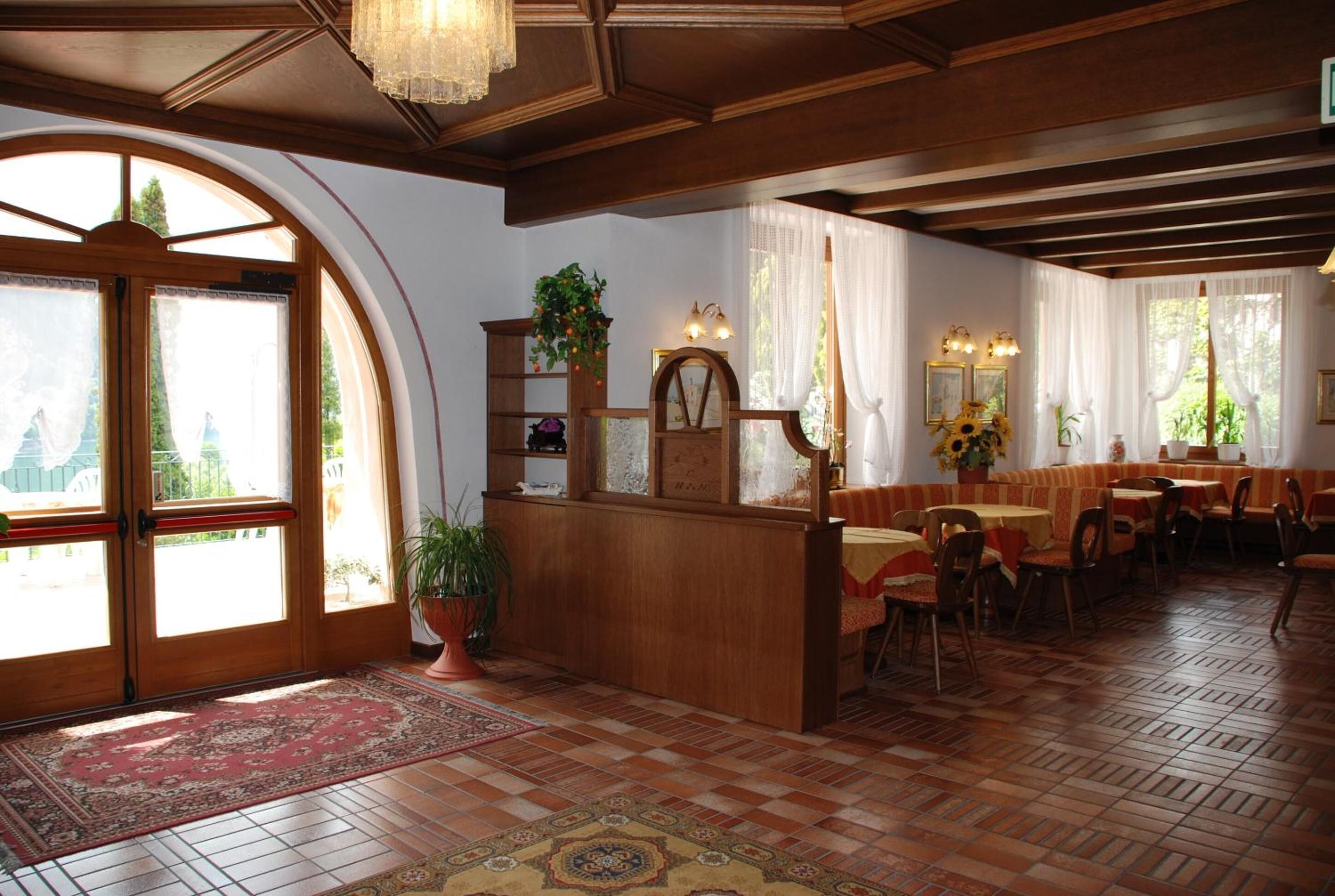 Ein traditionelles Gasthaus mit Holzmöbeln, einer zentralen Rezeption und einem Essbereich mit Tischen und Stühlen.