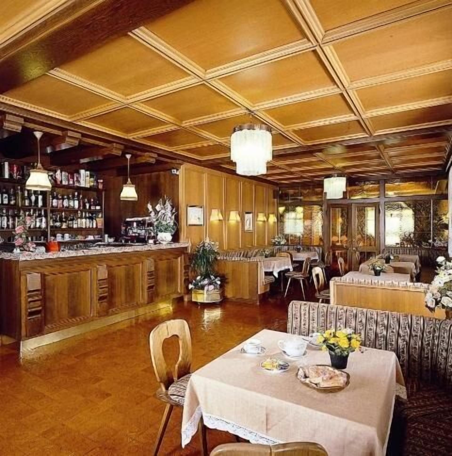Un restaurant avec des boiseries, un coin bar et des tables dressées pour le service.