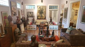 A living room with patterned sofas, a coffee table with decorative items, and various artworks on the walls.