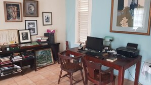 A home office with a desk, two chairs, a computer, and various framed pictures on the wall.