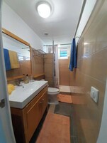 Un baño pequeño con lavamanos, inodoro y zona de ducha.