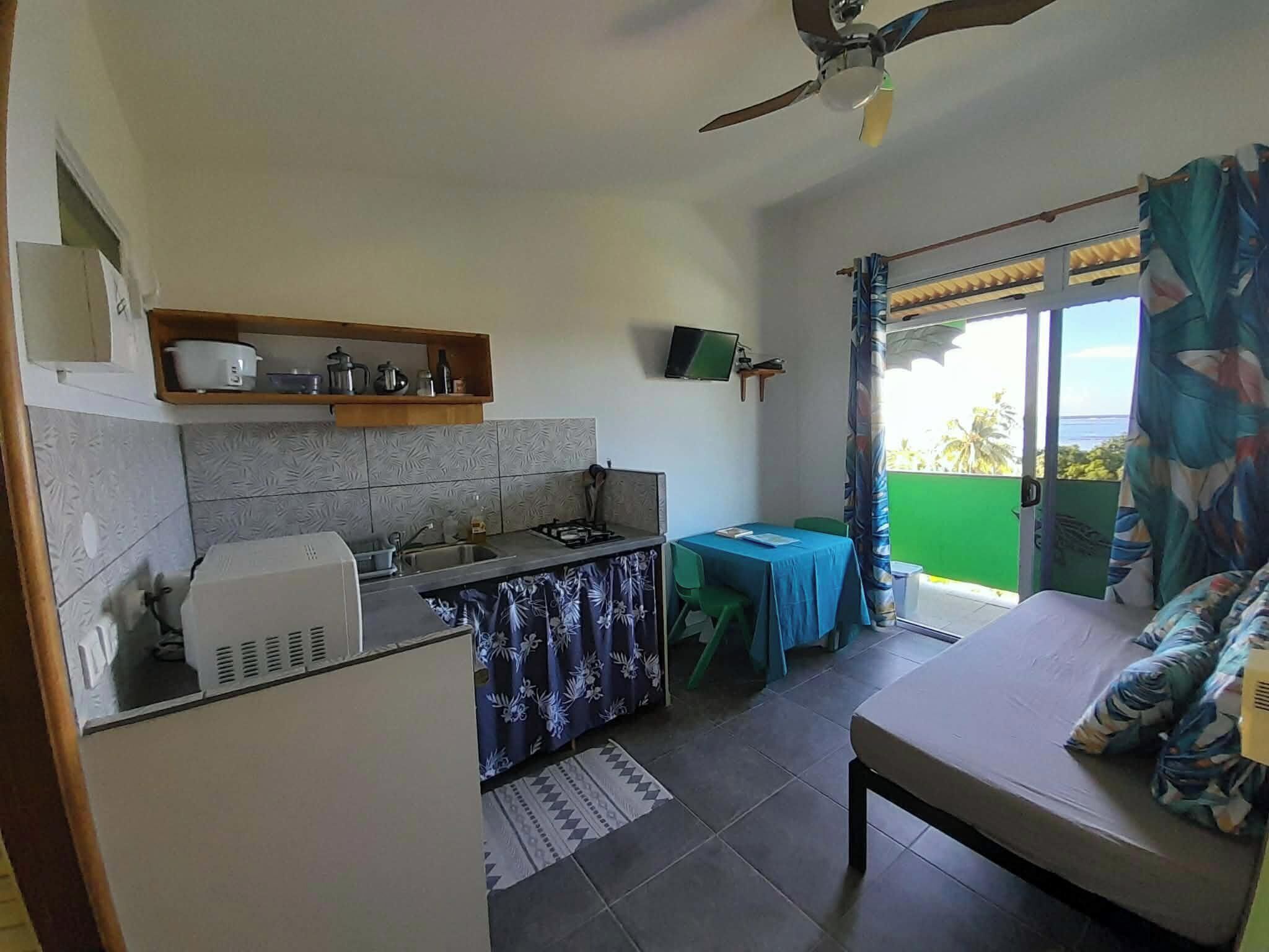 Habitación compacta con kitchenette, una cama, una mesita y vistas al exterior.