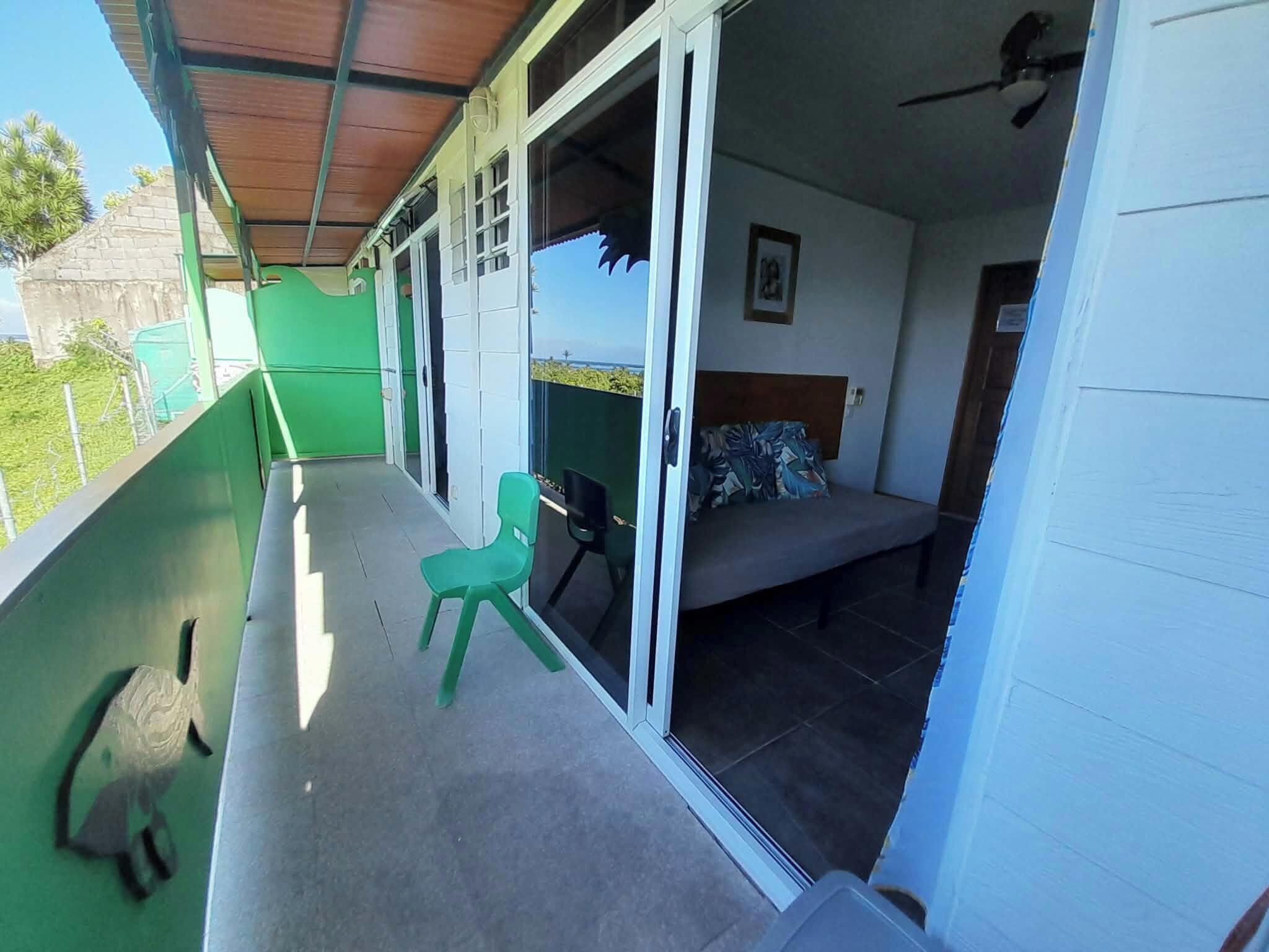 Una habitación con cama, una silla y un balcón al que se accede por un ventanal corredero.