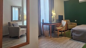A hotel room with a wooden desk, two chairs, a sofa, a mirror, a lamp, and a trash bin. - Male stepenice (Belgrade)