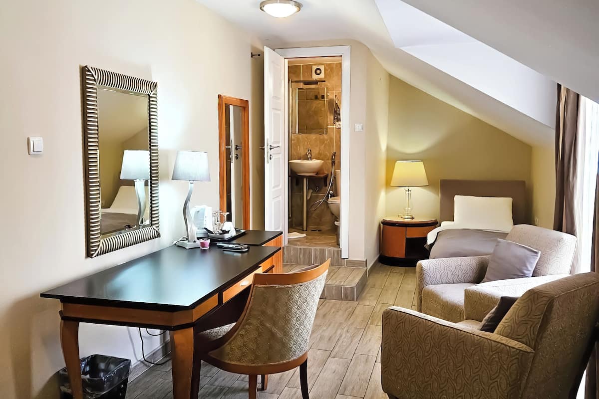 Ein Hotelzimmer mit Schreibtisch, zwei Stühlen, einem Bett, einem Badezimmer und einer Treppe.