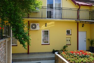 Un edificio amarillo con un balcón, una puerta y una ventana.