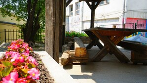 A garden area with a wooden bench and a wheelbarrow, surrounded by a concrete border and pink flowers. - Male stepenice (Belgrade)