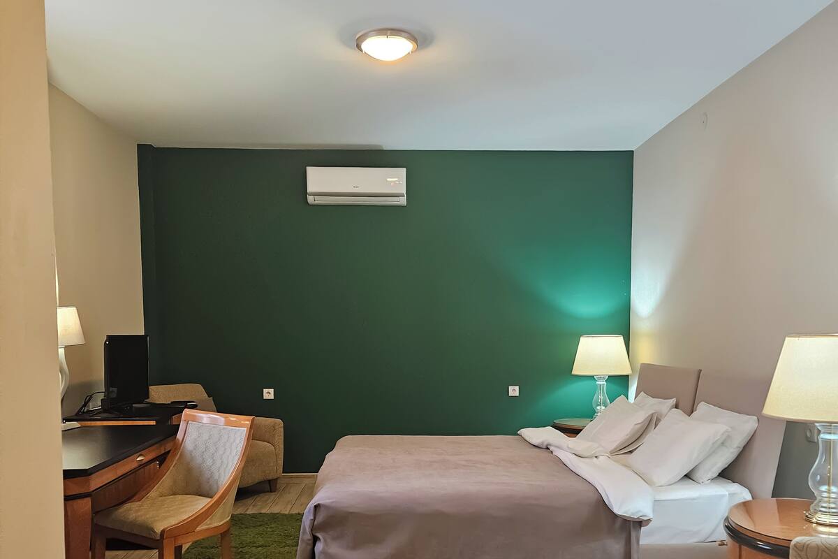 Ein Hotelzimmer mit einem Bett, einem Schreibtisch, einem Sessel und einer grünen Wand.