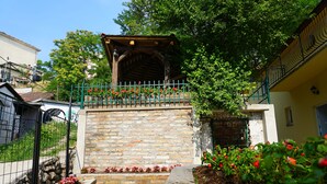 A stone staircase leading to a wooden pergola with a metal railing, surrounded by red flowers and greenery. - Male stepenice (Belgrade)