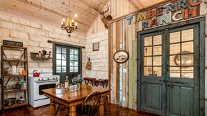 A rustic kitchen with a wooden table, a stove, and a sign reading "Timberro Ranch". - TimberRose B&B (Fredericksburg)