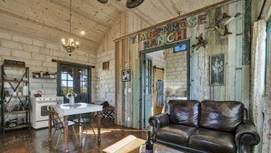 A rustic interior with a dining area, a leather sofa, and a sign reading "Timberrose Ranch". - TimberRose B&B (Fredericksburg)