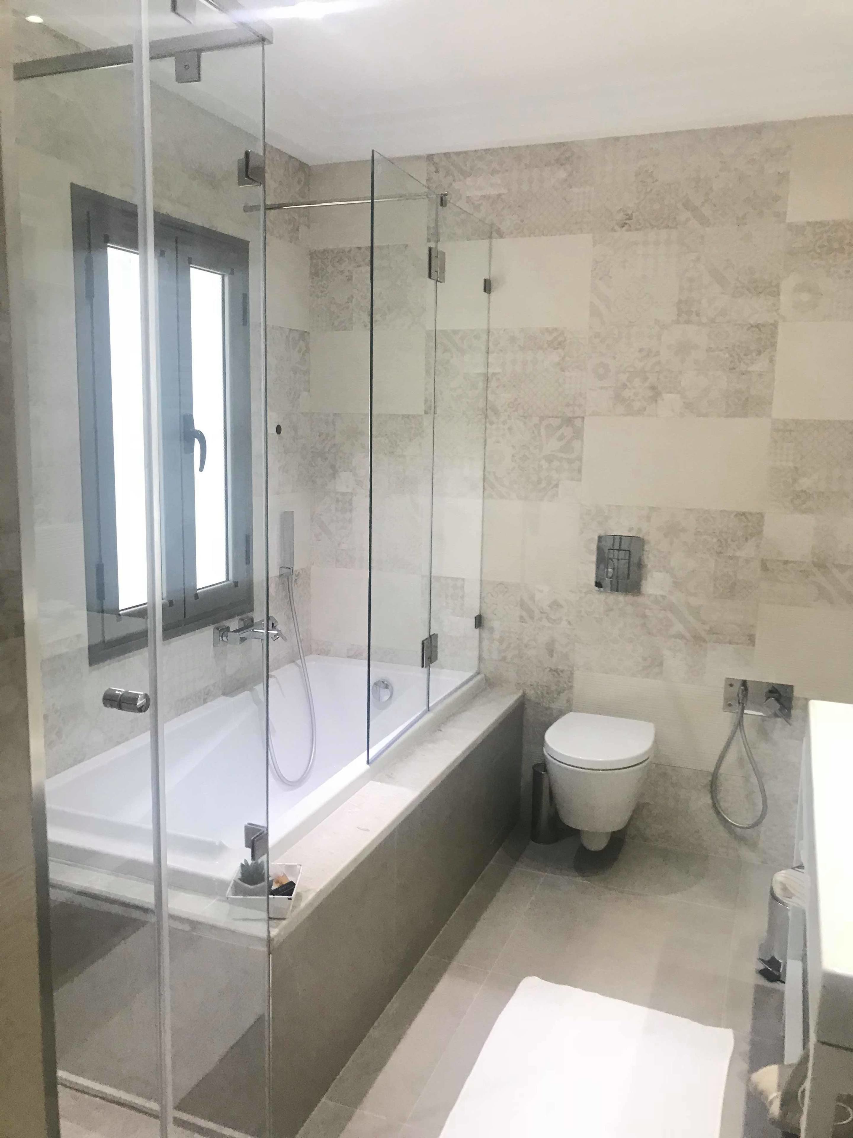 Une salle de bain moderne avec une douche à parois de verre, une baignoire sur pieds et des toilettes.