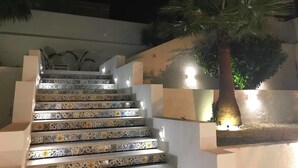 A staircase with patterned tiles leading up to a landing, surrounded by walls and a palm tree. - Dar Corniche La Marsa - Adults Only (La Marsa)