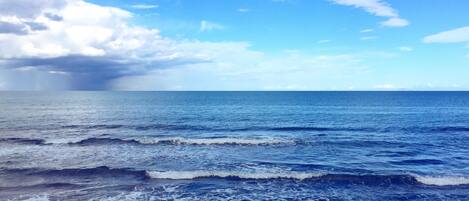 A beach with waves and a partly cloudy sky.