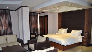 A modern hotel room with a large bed, a sofa, a coffee table, and a nightstand. - Assala (Oran)