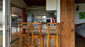 A kitchen with a refrigerator, stove, and microwave. There are three wooden chairs in front of a table. - Casa Odi-SEA - Portasol Vacation Rentals (Savegre)