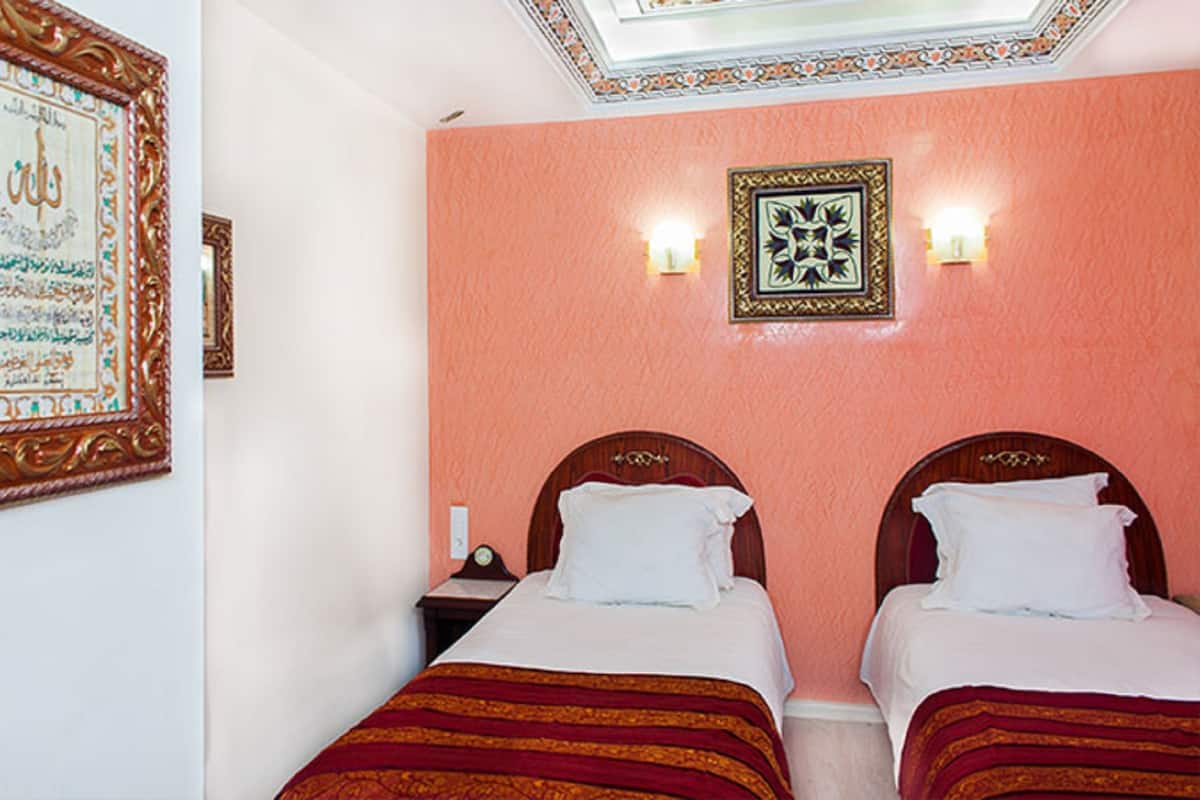 A hotel room with two beds, a nightstand, and a wall with decorative frames.