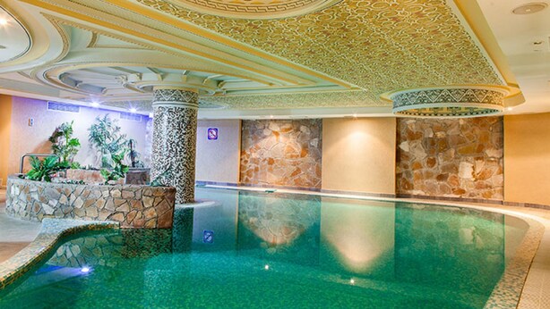 Una piscina interior con paredes de piedra y un techo decorativo.
