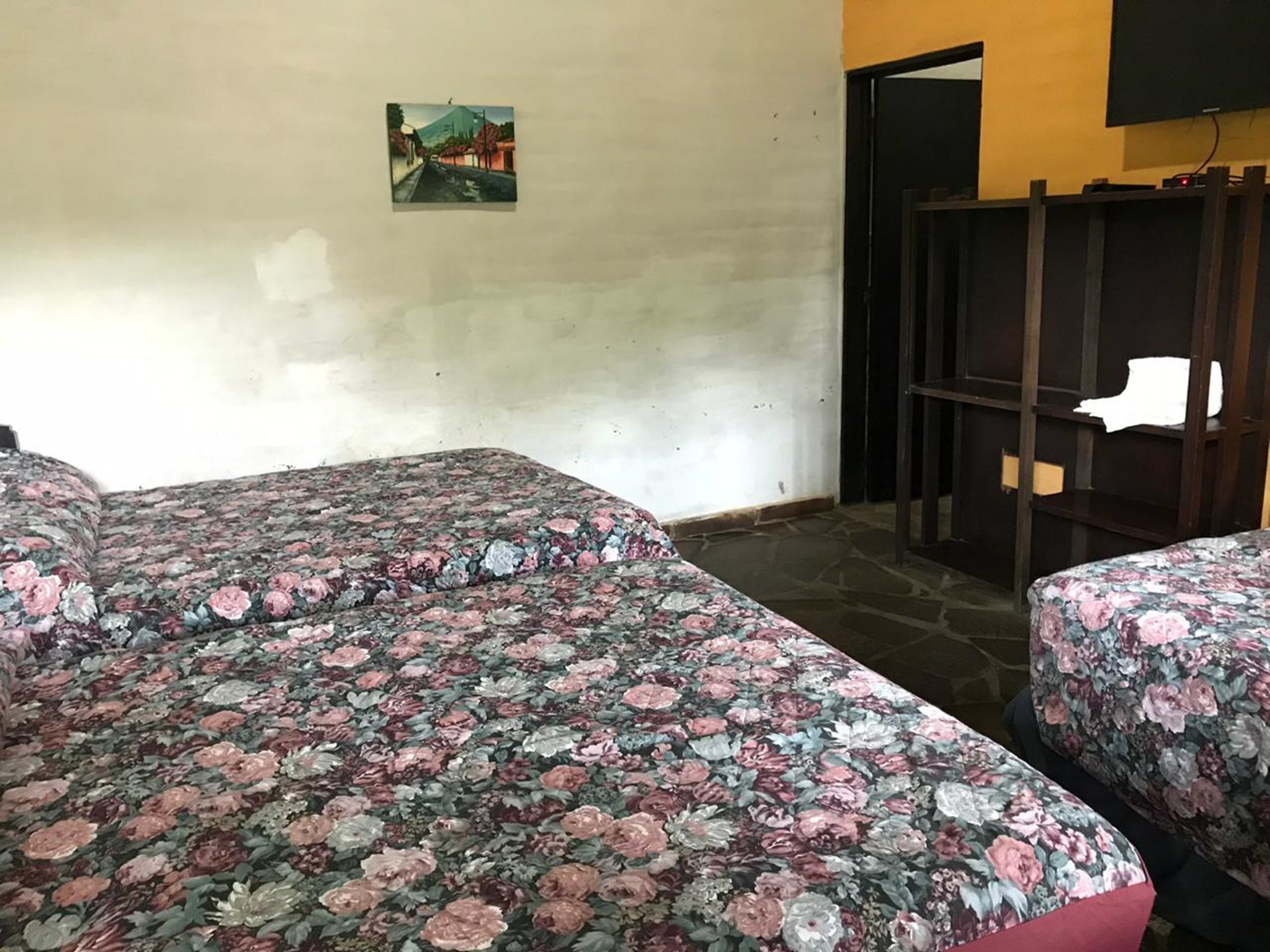 A room with two beds, a painting on the wall, and a wooden partition.