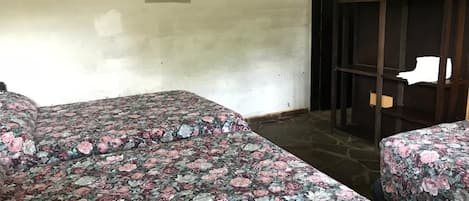 A room with two beds, a painting on the wall, and a wooden partition.