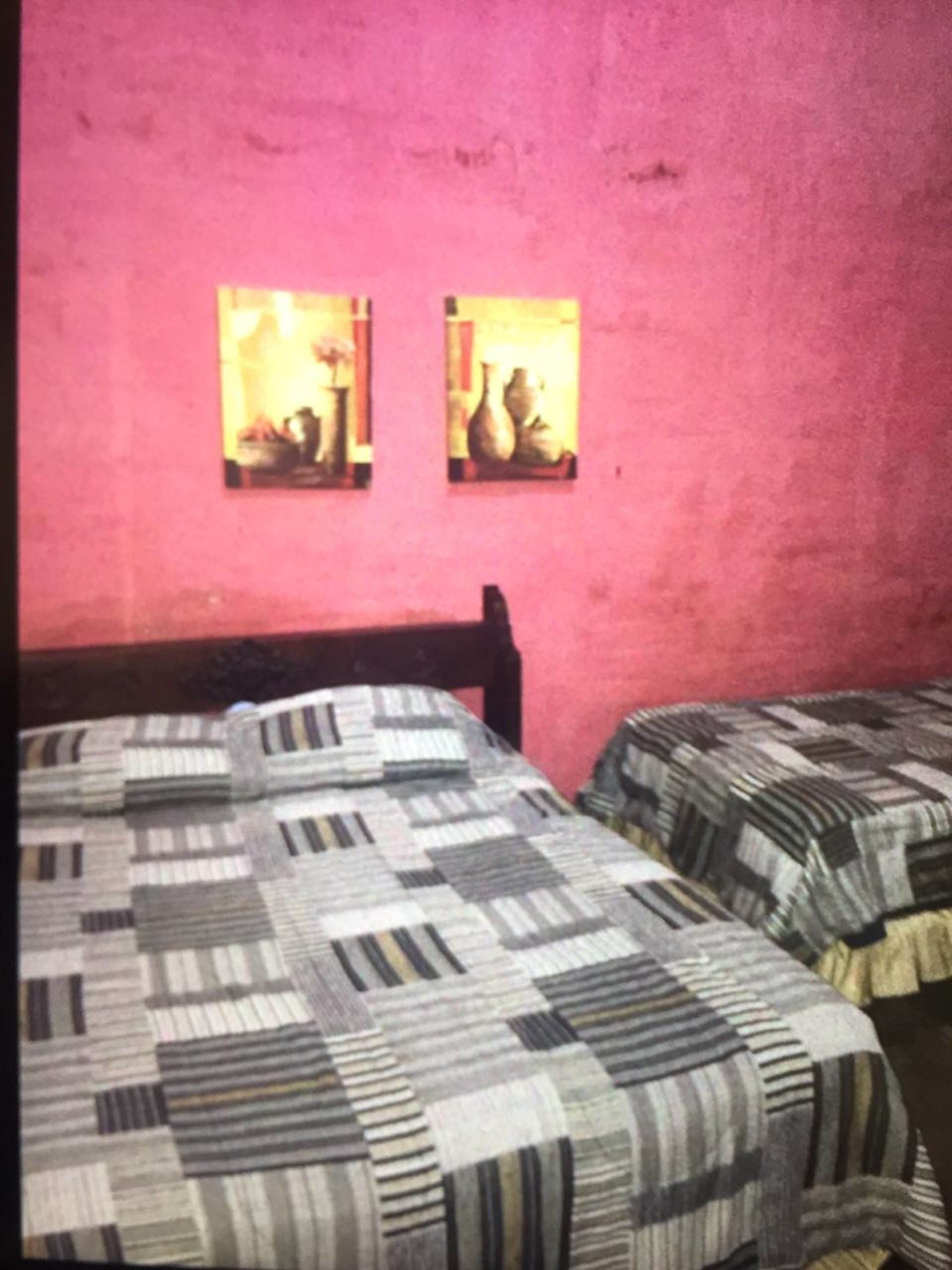 Una habitación con dos camas, cada una con una colcha estampada. Hay dos cuadros en la pared.