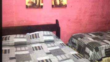 Una habitación con dos camas, cada una con una colcha estampada. Hay dos cuadros en la pared.