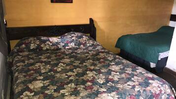 Un dormitorio con una colcha estampada con motivos florales, un cabecero de madera y dos cuadros en la pared.