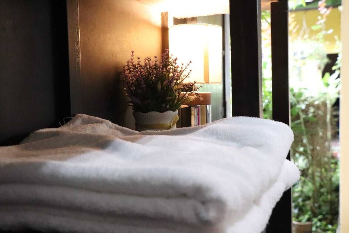 A neatly folded white towel on a window sill, a small potted plant, and a stack of books.