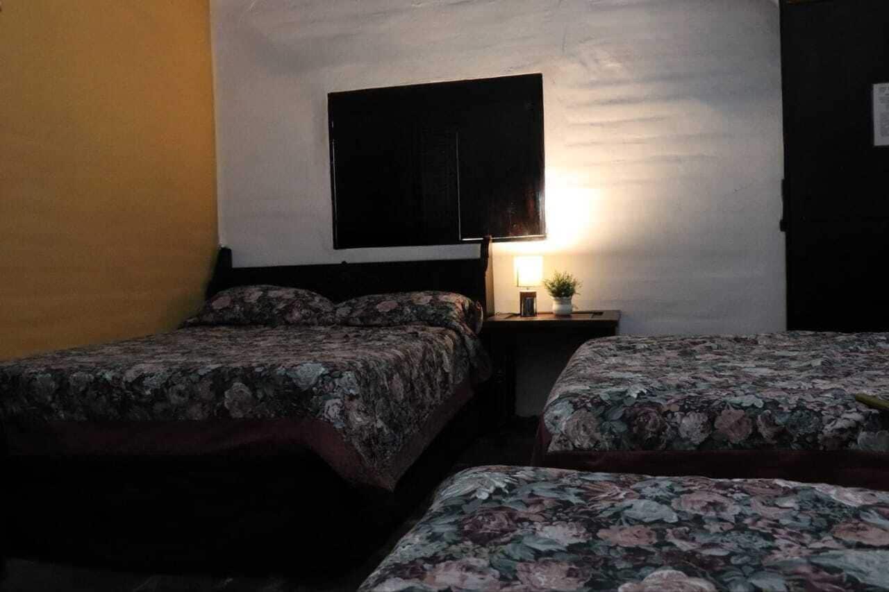 Una habitación con dos camas, una mesita de noche con lámpara y una obra de arte grande y oscura en la pared.