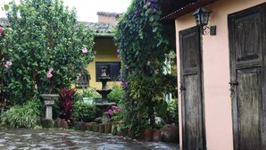 A courtyard with a stone pathway, a fountain, and lush greenery. - Hotel Villa Santo Domingo (Concepcion de Ataco)