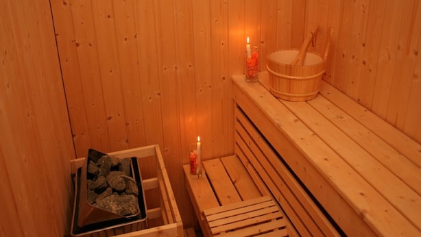 A wooden sauna with benches, a wooden bench, a candle, and a bucket. - Hotel 2 Horloges (Oran)