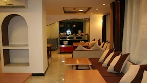 A modern hotel room with a living area, a kitchen in the background, and a dining area. - Hotel 2 Horloges (Oran)
