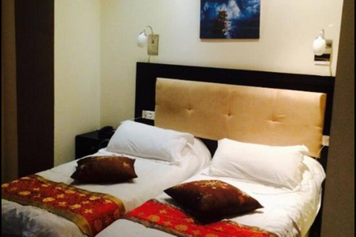 Ein Hotelzimmer mit einem großen Bett, zwei Nachttischen, einem Beistelltisch und einem Gemälde an der Wand.