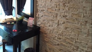 A room with a stone wall, a black desk with a mirror, a TV mounted on the wall, and a window with curtains. - Hotel 2 Horloges (Oran)