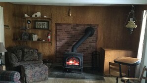 A cozy living room with a brick fireplace, a sofa, a chair, and a small table.