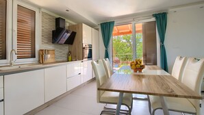 Una cocina moderna con armarios blancos, una encimera de madera y una zona de comedor con mesa y sillas.