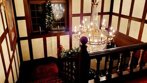 Una imponente escalera con un candelabro, un árbol de Navidad y una ventana con vistas.