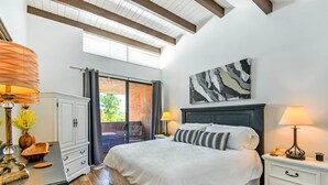 Une chambre à coucher avec un grand lit, une table de chevet, une commode et une fenêtre avec des rideaux.