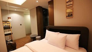 A hotel room with a bed, a small round table, a shelf with shoes, and two framed pictures on the wall. - Namyangju Bukhangang Dolce Casa Hotel (Namyangju)