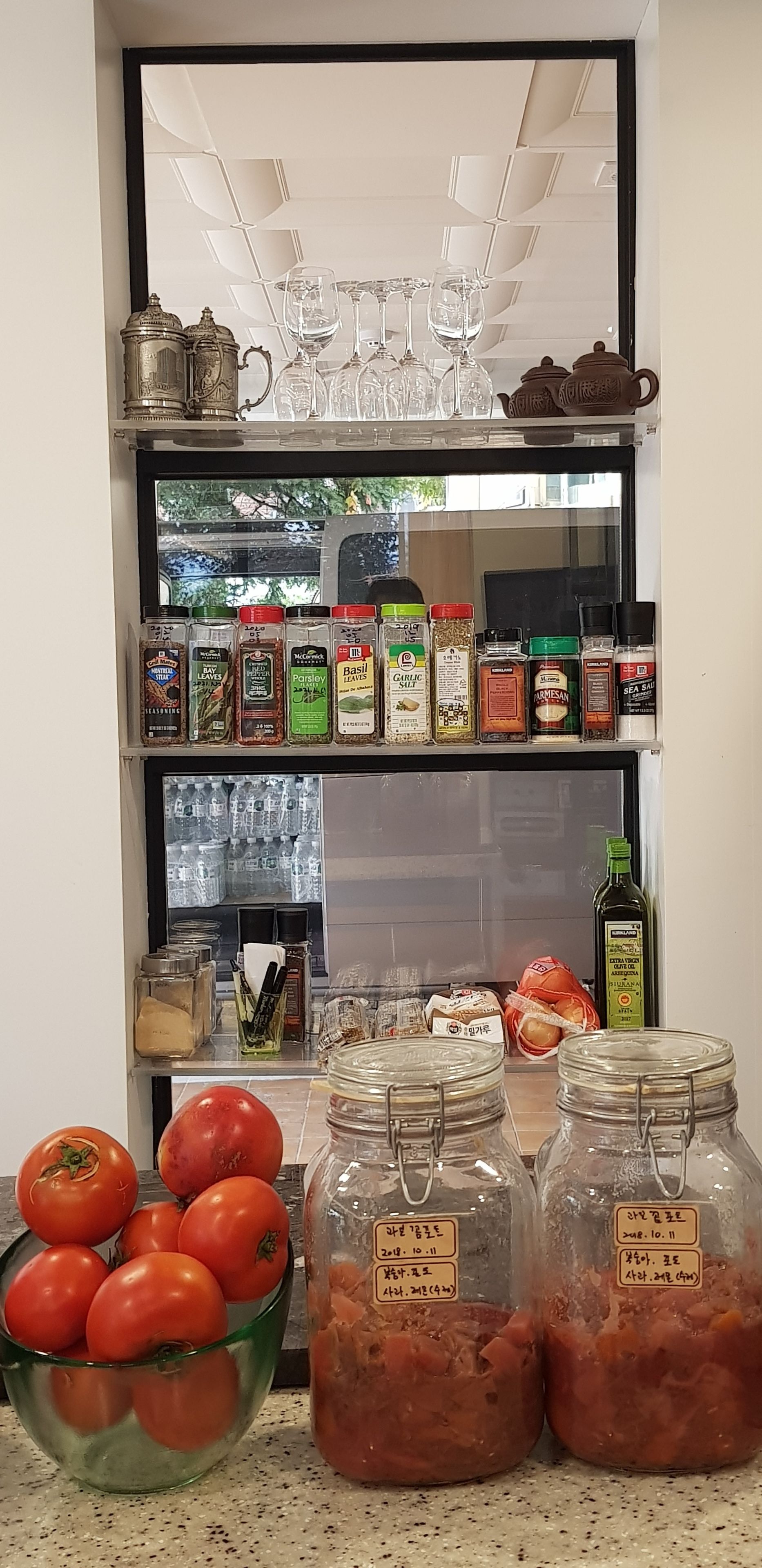 Un plan de travail de cuisine avec une variété de condiments, d’épices et un bol de tomates.