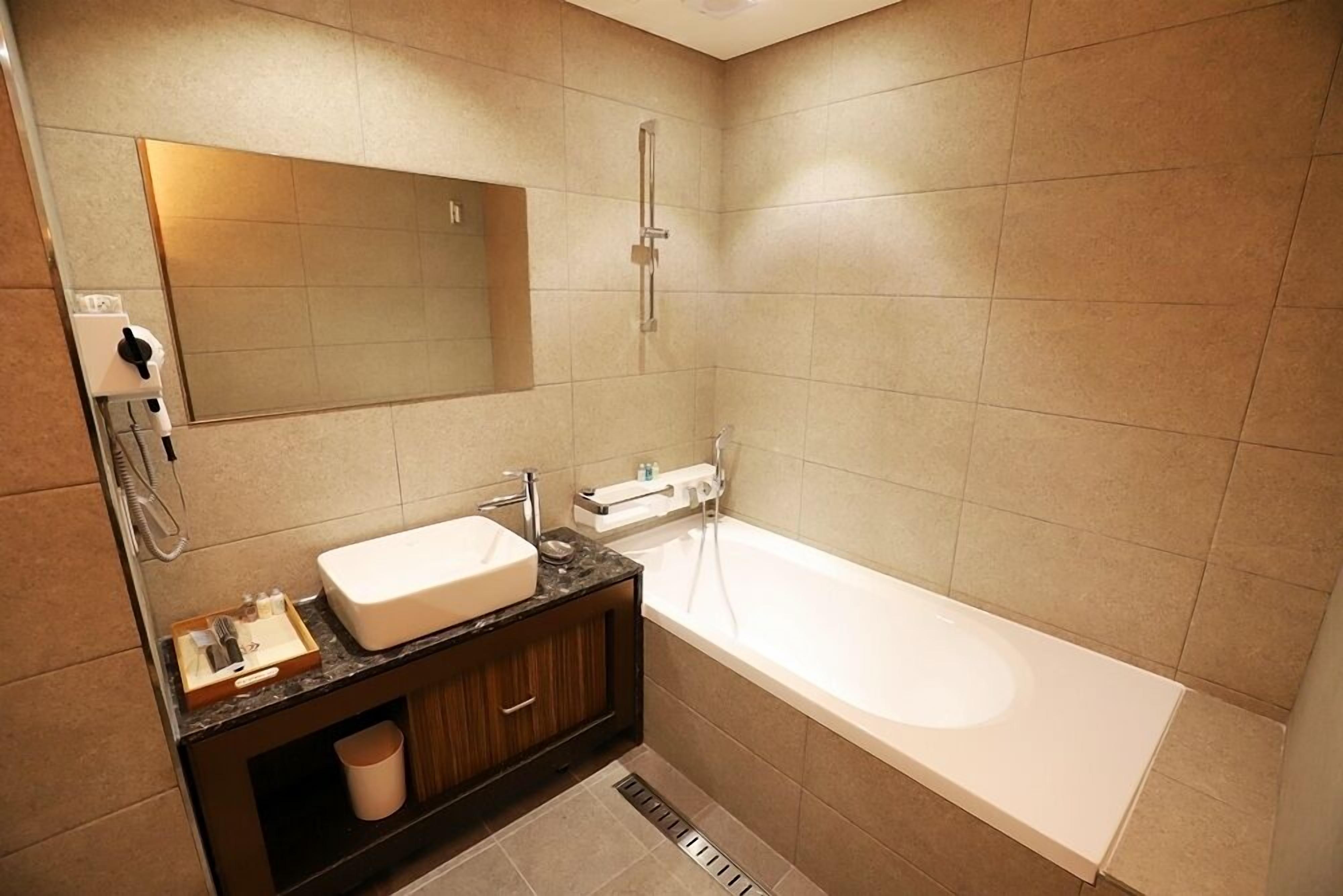 A modern bathroom with a large bathtub, a vanity with a mirror, and a shower.